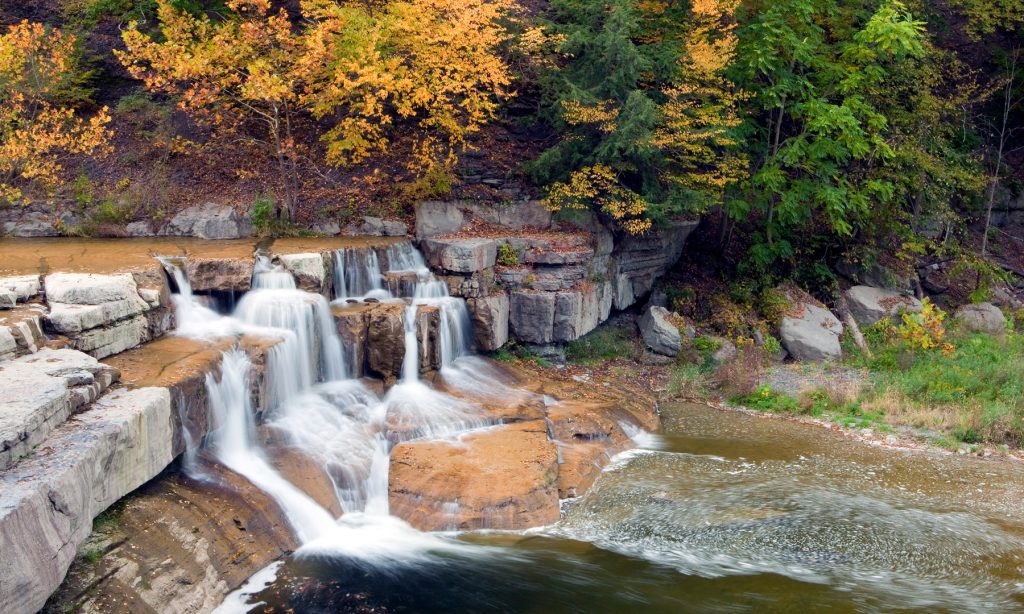 Lower falls at Taughannock Falls State Park in the fall with fall color image for the 5 Best parks in the finger lakes to see fall color for the Gould Hotel in Seneca Falls, New York